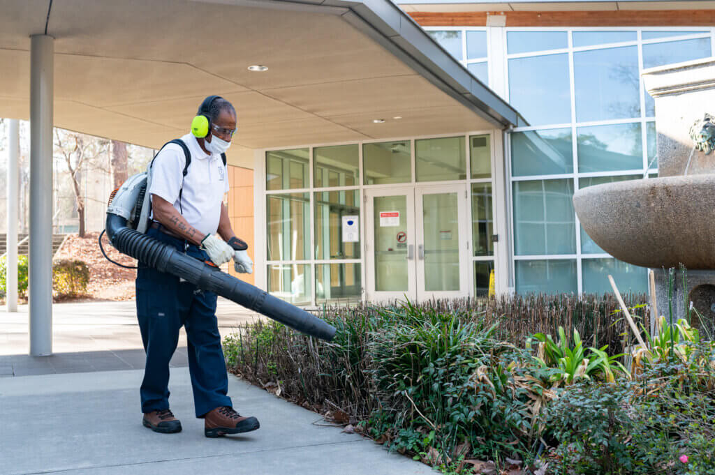 man blowing leaves at park and recreation facility