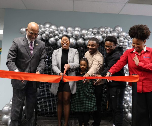 Picture of people standing behind a red ribbon, about to cut it for the grand opening of 5 Star Dental Academy