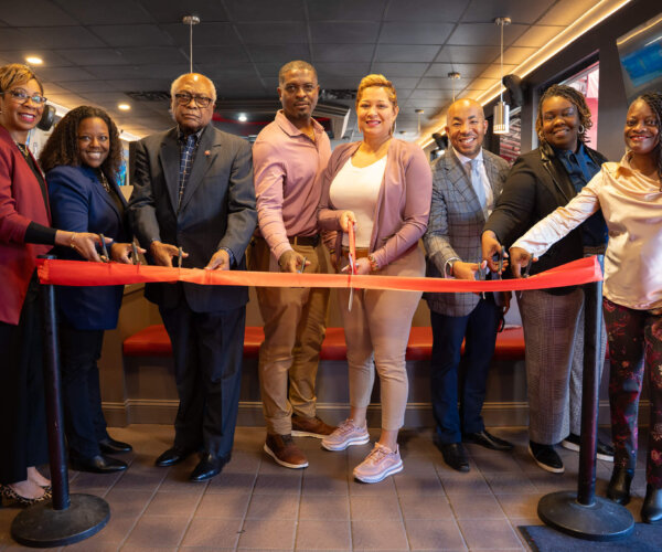 Picture of people standing behind a red ribbon, about to cut it for the grand opening of Red Zone Sports Diner