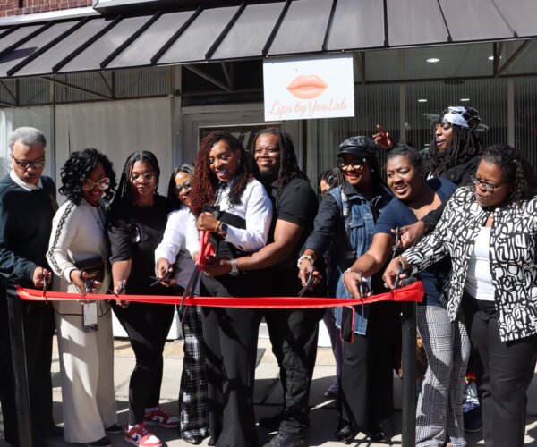 Picture of people standing behind a red ribbon, about to cut it for the grand opening of Lips by U Lab