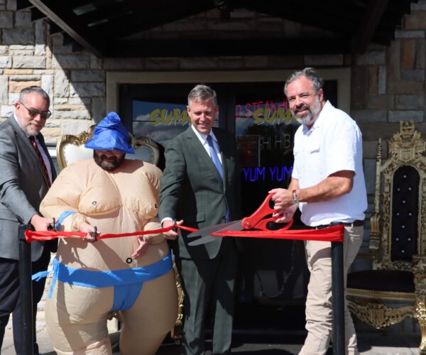 Picture of people standing behind a red ribbon, about to cut it for the grand opening of Sumo Japanese Steakhouse