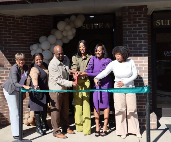 Picture of people standing behind a red ribbon, about to cut it for the grand opening of New Vision Med Spa
