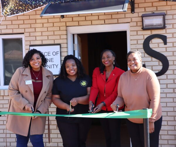 Picture of people standing behind a red ribbon, about to cut it for the grand opening of A Piece of Divine Serenity