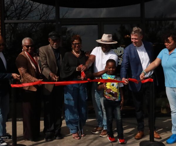 Picture of people standing behind a red ribbon, about to cut it for the grand opening of Crown & Ash Cigar Lounge